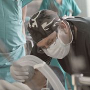 Médicos e enfermeiros atendem um paciente durante um procedimento hospitalar.