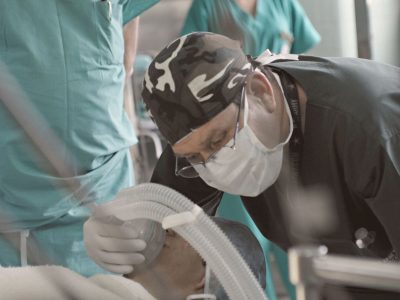 Médicos e enfermeiros atendem um paciente durante um procedimento hospitalar.