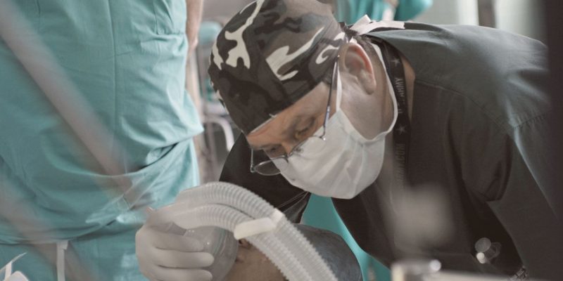 Médicos e enfermeiros atendem um paciente durante um procedimento hospitalar.