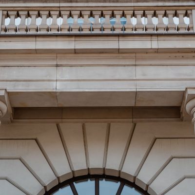 Fachada de prédio público neoclássico com colunas e sacada, vista durante o dia