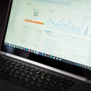 Laptop exibindo um painel de análise de dados em tempo real sobre uma mesa de trabalho.