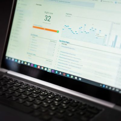Laptop exibindo um painel de análise de dados em tempo real sobre uma mesa de trabalho.