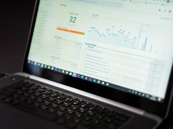 Laptop exibindo um painel de análise de dados em tempo real sobre uma mesa de trabalho.