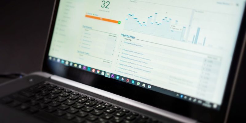 Laptop exibindo um painel de análise de dados em tempo real sobre uma mesa de trabalho.