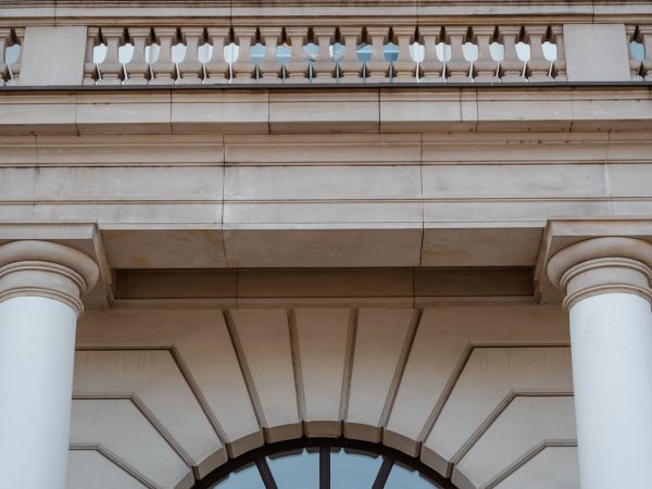 Fachada de prédio público neoclássico com colunas e sacada, vista durante o dia