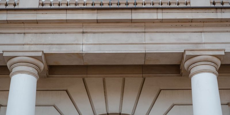 Fachada de prédio público neoclássico com colunas e sacada, vista durante o dia