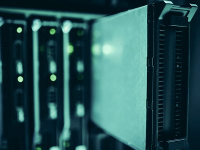 Close de racks de servidores em um data center moderno, com iluminação azul e equipamentos tecnológicos.