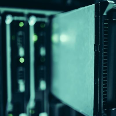 Close de racks de servidores em um data center moderno, com iluminação azul e equipamentos tecnológicos.