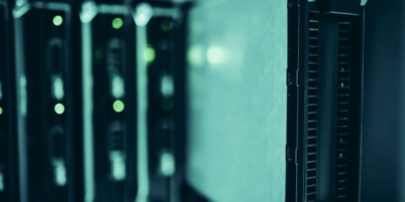 Close de racks de servidores em um data center moderno, com iluminação azul e equipamentos tecnológicos.