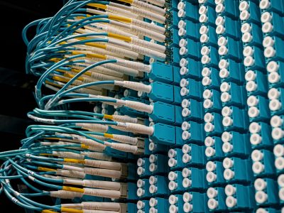 Cabos de fibra óptica conectados a um painel azul em um data center.